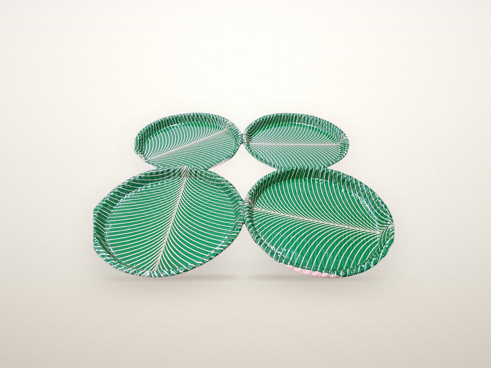 Four green leaf-print paper plates
